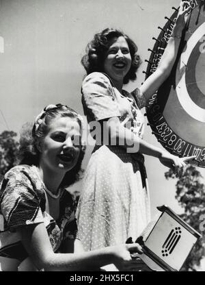 'Buy a ticket' -- Miss Australia entrants, Margaret Wood (Hornsby RSL) and June Allsop (Roseville RSL), help out on one of the stalls at the Horse Show at St. Ives today. The show was held to support local candidates in the Miss Australia Quest. October 23, 1948. Stock Photo