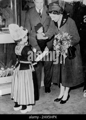 Queen At Ideal Home Exhibition -- The Queen receiving from 5-year-old Marijke Legerstee, the daughter of a Dutch Embassy Official, two dolls. There was a little Dutch boy for Prince Charles and a little Dutch girl for Princess Anne. The Queen wearing an emerald green coat accompanied by the Duke of Edinburgh visited the opening of the Ideal Home Exhibition in London on Monday. They inspected household gadgets from Britain and countries overseas, and the Duke asked his Equerry to collect ***** on certain objects he particularly admired. In the life-size Village on the hill the Royal couple Stock Photo