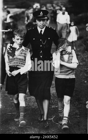 Tragic Moment. These two boys have just seen their pal drown. The arms of Policewoman Jennifer Goodchild comfort Robert Thompson and Keith Marden as they leave the tragedy scene-a Kent gravel pit. When their play- J mate fell in the boys ran for help-too late. June 30,1955. (Photo by Daily Mirror). Stock Photo