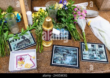 New York, NY, USA. 9th Mar, 2022. A banner asking people to pray for Ukraine, a box for donations, flowers, photos, a votive candle, and a Ukrainian flag and memorabilia sit in the rain outside the Holy Trinity Ukrainian Orthodox Cathedral in New York City's Little Italy. Credit: Ed Lefkowicz/Alamy Live News Stock Photo