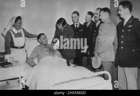 Lying on hospital bed at a Canadian Army base some where in the United Kingdom, Lieut. Col. Loren B. Hillsinger of New York receives distinguished service cross and order of the purple heart from Brig. Gen. L.K.Truscott Jr. for his valor in the dieppe raid, where he lost a leg. Other officers right to left are Lt. Col. D. E. Williams, Col. H. D. Campbell, Brig, F. O'D. Hunter, Brig. Gen. H.A. Craid, and group captain A. H. Willetts of the RAF. nurse is Andree Dalton, of Prince Edward island, Canada. September 20, 1942. (Photo by AP Wirephoto). Stock Photo