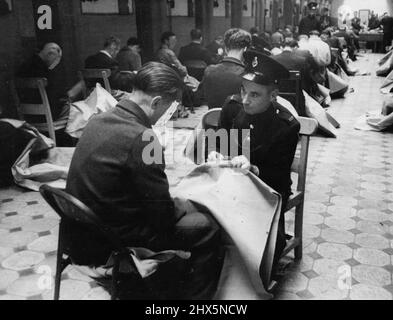 Hour after hour, week in, month out, the prisoners make mailbags - eight stitches to the inch, 384 inches to the bag. Davidson initiates a newcomer. It's another old prison time-killer. April 12, 1950. (Photo by Bert Hardy, Picture Post). Stock Photo