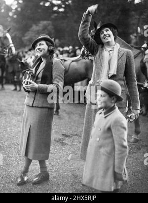 Waving to Her Children - Lady May Abel Smith (left) waving to her two children who are recovering from colds and watched the meet from the windows of the manor. Also seen in Mrs. Haygate. The Queen Hounds met today at Beaumanor when Mrs. and Captain and Lady May Abel Smith were the host and hostesses. December 30, 1936. (Photo by L.N.A.). Stock Photo