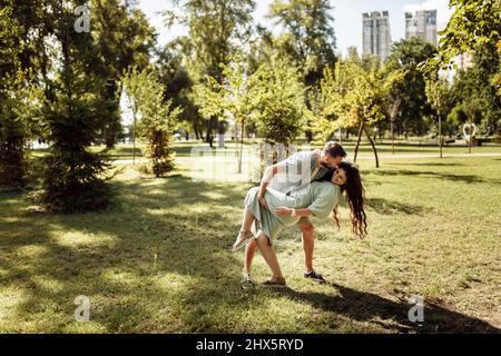 Overjoyed couple dancing at the park, loving husband hold in arms beautiful wife, pretty woman smiling, enjoy happy time together, relaxing, healthy Stock Photo