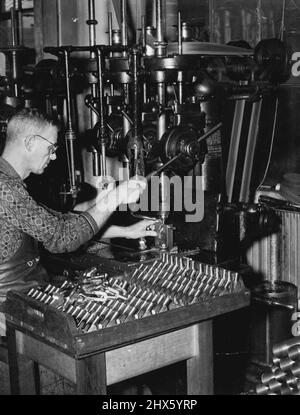 Lithgow Small Arms Factory is turning out Vickers guns in ever-increasing numbers. Workman is here shown using precision drilling machine. By his side is a tray of completed Vickers gun components. July 22, 1940.;Lithgow Small Arms Factory is turning out Vickers guns in ever-increasing numbers. Workman is here shown using precision drilling machine. By his side is a tray of completed Vickers gun components. Stock Photo