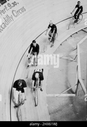 The First International Six-Day's Bicycle race in London started at Midnight, July 15th., On a specially constructed track at the Olympia, London. The riders - many of whom are competitors from several countries - will eat and sleep in full view of the spectators. The track is banked to an angle of 52 degrees, and takes eight laps to the mile. Some of the competitors taking it easy at the bottom of the track during a lull in the sprinting. July 16, 1934. (Photo by Sport & General Press Agency L Stock Photo