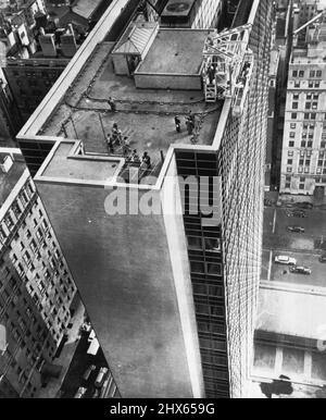 Tracking Down Dirty Windows - Window washers' elevator is demonstrated on rood of new Lever House, 24-story window wall and stainless steel building under construction at Park Avenue and 53rd Street. Car runs on roof tracks and supports a push-button scaffold which runs on vertical tracks down the sides of the building. Device is needed because windows of completely air-conditioned building do not open. There is no place on sheer glass walls where a washer can climb put or fasten a safety belt. Stock Photo