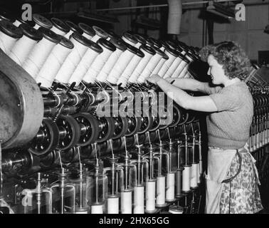 Sheep Supp. - At John Vicars Pty Ltd Marrickville. The roving operation in the drawing dept. Here the operator is fitting a full spool in the machine which draws the combed wool into fine slivers ready for spinning. May 28, 1952. (Photo by Frank Albert Charles Burke/Fairfax Media). Stock Photo