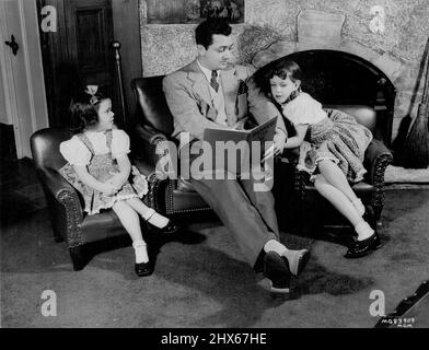 Robert Young, Metro-Goldwyn-Mayer actor, spends his days off from studio work reading and frolicking with his two daughters, Carole Ann and Barbara Queen. The actors newest film for *****. October 29, 1947. Stock Photo