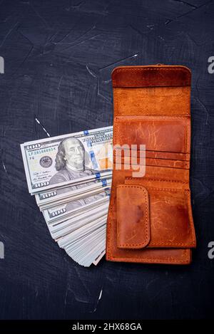 Financial and business concept. Dollars in a brown wallet on a black background. Stock Photo