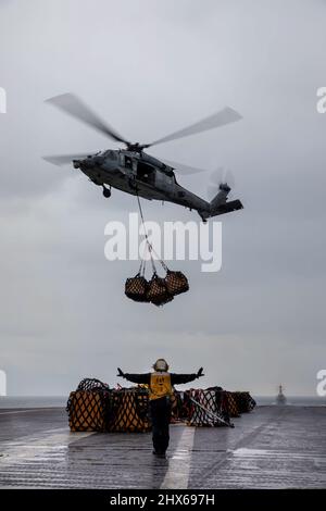 220308-N-QI593-1425 IONIAN SEA (Mar. 8, 2022) Aviation Boatswain's Mate (Handling) 3rd Class Aubrey Bogle, from Dallas, directs the pilot of an MH-60S Sea Hawk helicopter, attached to the “Dragon Slayers” of Helicopter Sea Combat Squadron (HSC) 11, on the flight deck of the Nimitz-class aircraft carrier USS Harry S. Truman (CVN 75) during a replenishment-at-sea, Mar. 8, 2022. The Harry S. Truman Carrier Strike Group is on a scheduled deployment in the U.S. Sixth Fleet area of operations in support of U.S., allied and partner interests in Europe and Africa. (U.S. Navy photo by Mass Communicatio Stock Photo