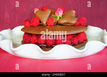 A giant chocolate macaron cake with fresh raspberries and rose flowers Stock Photo