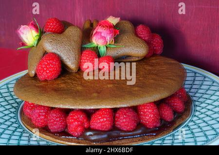 A giant chocolate macaron cake with fresh raspberries and rose flowers Stock Photo