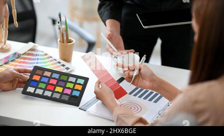 Cropped, close-up image A team of graphic designers were talking and discussing the project in the meeting. Female designer holding a colour swatch sa Stock Photo