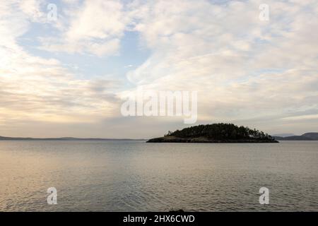 dramatic light streaming through wispy clouds reflecting in calm ocean water Stock Photo