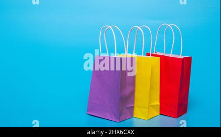 three colored paper bags on a blue background Stock Photo