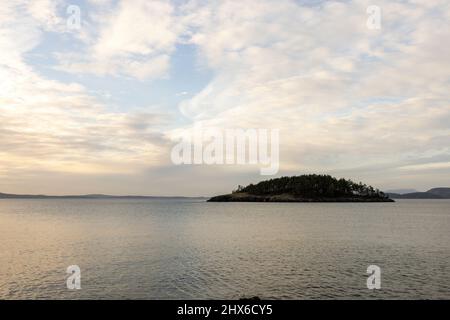 dramatic light streaming through wispy clouds reflecting in calm ocean water Stock Photo