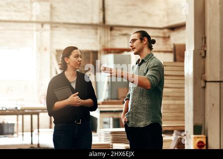 Were always discussing ways of growing our business. Cropped shot of two young carpenters at work in their workshop. Stock Photo