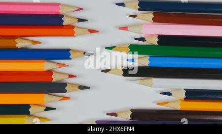 Many colored pencils are arranged around the edges of the image as a frame. In the center is an empty background with space for text. Mock up with copy space. Stock Photo