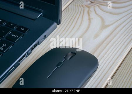 Close up of a laptop and a wireless mouse on a light wooden surface. Stock Photo