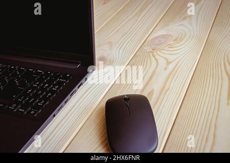 Close up of a laptop and a wireless mouse on a light wooden surface. Stock Photo