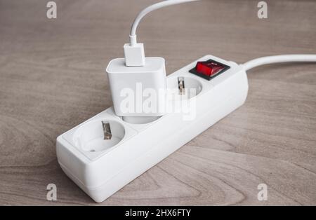 Charger adapter with USB cable connected to Power Strip with red switch. Stock Photo