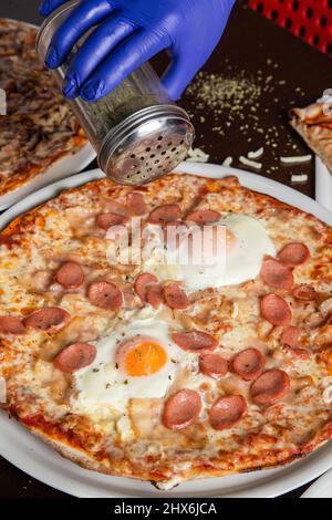 Pizza chef's hand topping a pizza Stock Photo