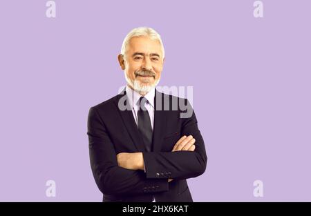 Portrait of happy senior businessman in suit standing on purple studio background Stock Photo