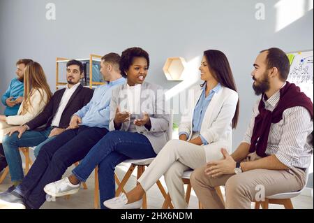 Diverse team of happy young people talking during business training meeting in office Stock Photo