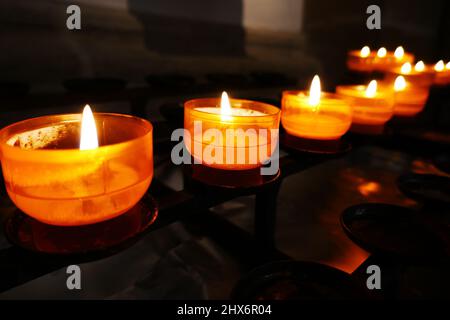 Row with yellow prayer tea lights in a roman catholic church Stock Photo