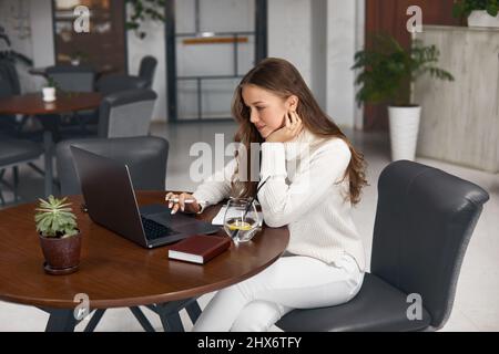 Young woman working on laptop while sitting in cafe Stock Photo