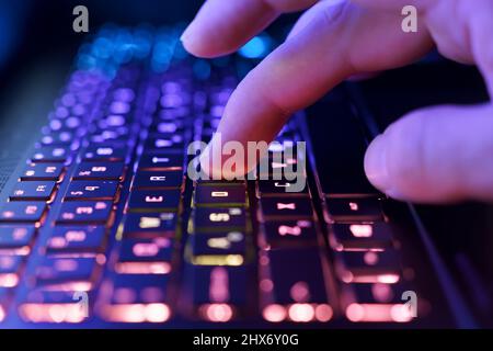 Working on a neon computer keyboard with colored backlighting. Computer video games, hacking, technology, internet concept. Selected focus. High quality photo Stock Photo