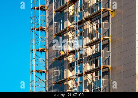 Scafolding on the exterior multistory house wall.  Block-of-flats heat insulation with mineral wool. Stock Photo