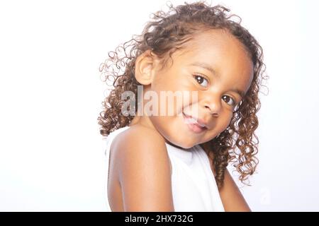 A little brown girl with brown hair, well-defined curls gesturing to express various expressions and messages through her eyes, her face and her subli Stock Photo