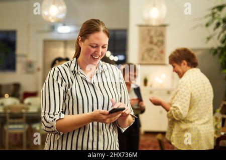Woman with smartphone during meeting in cafe Stock Photo