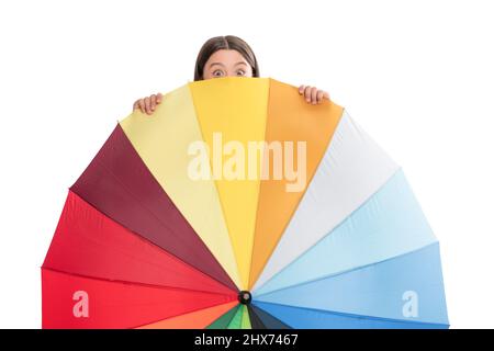 child hiding behind colorful parasol. kid with rainbow umbrella isolated on white. Stock Photo