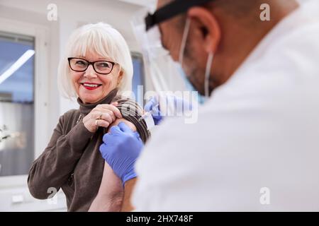 Senior woman getting vaccinated against Covid-19 Stock Photo