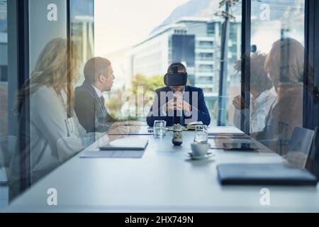 Breaking international barriers. Shot of a businessman wearing a VR headset during a meeting in the boardroom. Stock Photo