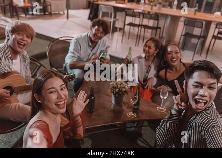 Group of young friends enjoying meal and taking selfie photos in pub and restaurant Stock Photo