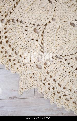 Handmade carpet knitted from natural threads, flooring, natural cotton. Beige handmade carpet. Knitted decorative item Stock Photo