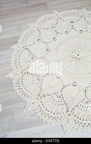 Handmade carpet knitted from natural threads, flooring, natural cotton. Beige handmade carpet. Knitted decorative item Stock Photo