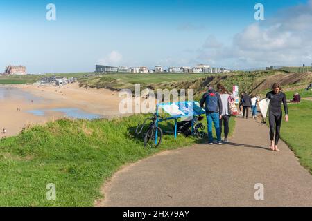 Visitors enjoying the afternoon Autumn sunshine on the footpath overlooking Fistral Beach in Newquay in Cornwall. Stock Photo