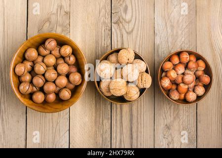 natural organic macadamia, walnut, hazelnut nuts in wooden bowl on wooden background Flat lay Top view Healthy snack Nuts with essential oil rich in v Stock Photo
