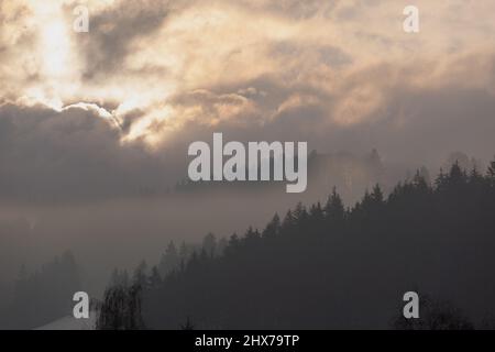 The brightness of the sun forms very different clouds and makes the mountain very mysterious. Stock Photo