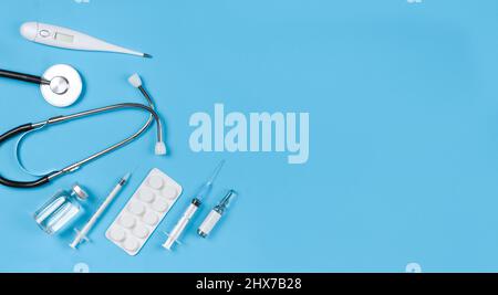 Stethoscope, vials, syringe, thermometer, pills blister on a blue background with copy space. Stock Photo