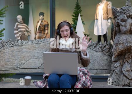 A young woman talking to someone via laptop and waving hi Stock Photo
