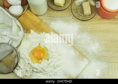 Fresh and raw chicken egg in flour. Bright color of egg yolk and wheat flour. Ingredients for baking on the table. Background with copy space for text Stock Photo