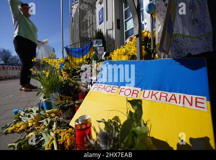 Hamburg, Germany. 10th Mar, 2022. An employee of the Consulate General of Ukraine sorts the discarded flowers and posters in front of the entrance to the consulate. Credit: Marcus Brandt/dpa/Alamy Live News Stock Photo