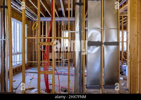 Installing hot red pex pipe and air ventilation and cleaning system pipes on the wall, amongst wooden beams Stock Photo