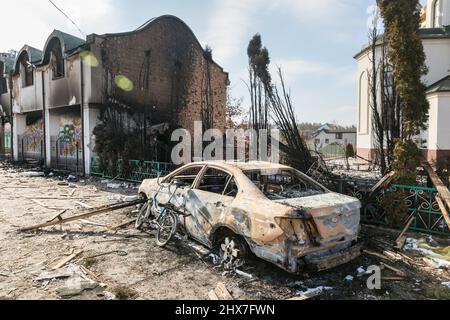 IRPIN, UKRAINE - Mar. 09, 2022: War in Ukraine. Chaos and devastation on the outskirts of Irpin. Damaged church and burned car as a result of the bombardment of a peaceful city Stock Photo